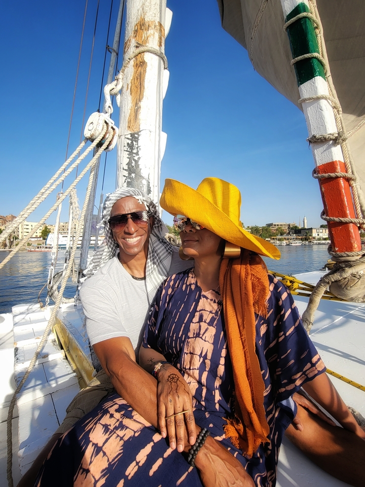 Two people on a boat with a river view in the background.