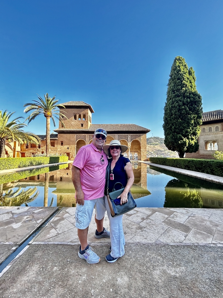 Couple posing in front of historic architecture and water.