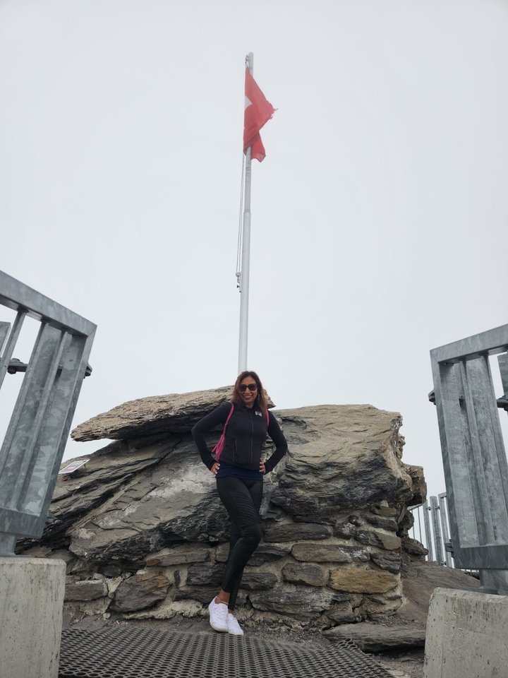 Femme debout sur un affleurement rocheux avec un ciel nuageux.