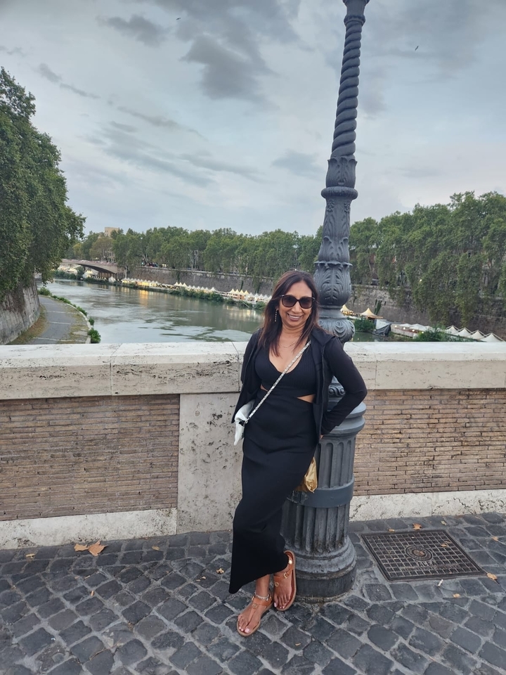 Femme debout sur un pont avec vue sur une rivière et des arbres.