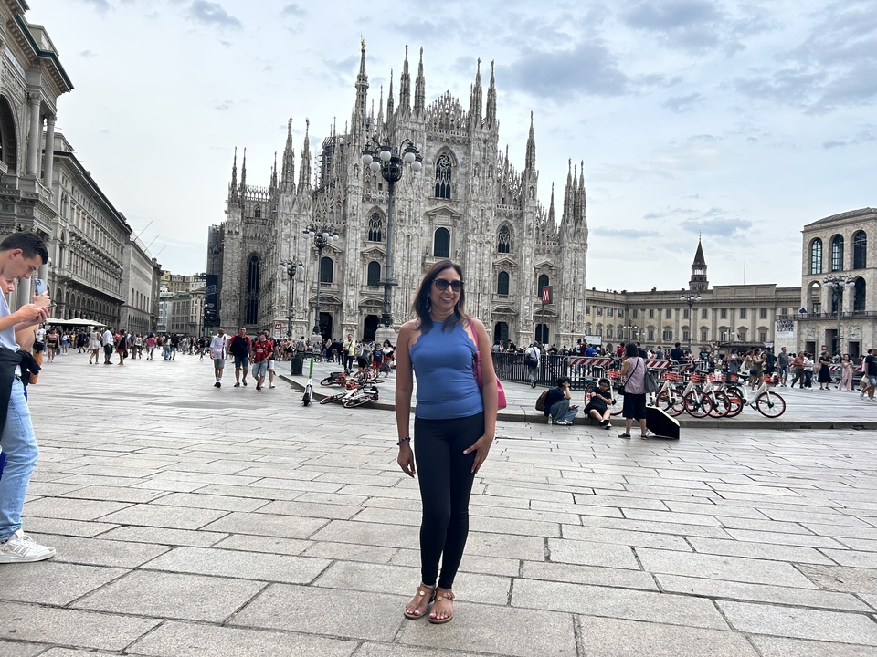 Femme posant devant la cathédrale de Milan sur une place animée.