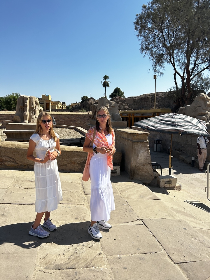 Deux femmes posant devant des ruines antiques avec des statues.