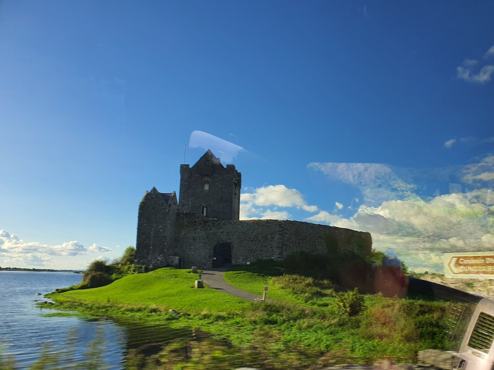 Un château historique au bord d'un plan d'eau sous un ciel bleu.