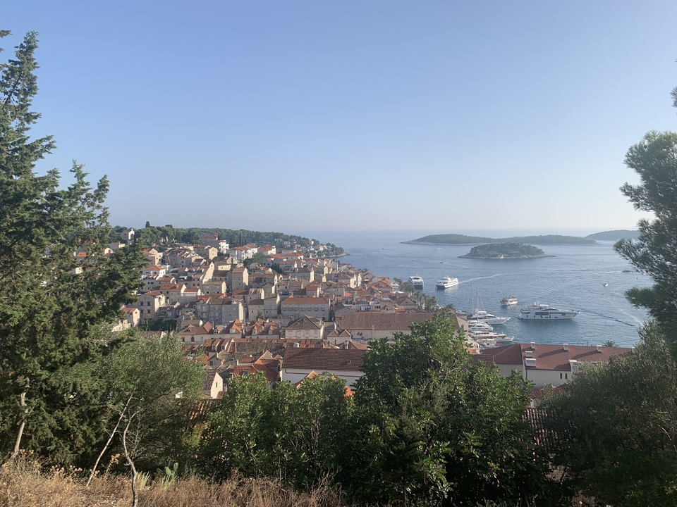 Vue panoramique d'une ville côtière avec des bateaux et des îles au loin.