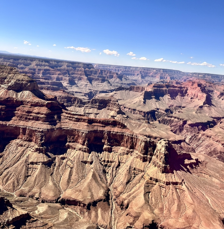 Grand Canyon with layered rock formations under a bright blue sky.
