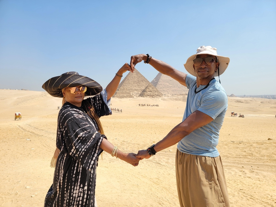 Couple posant devant les pyramides emblématiques dans le désert.