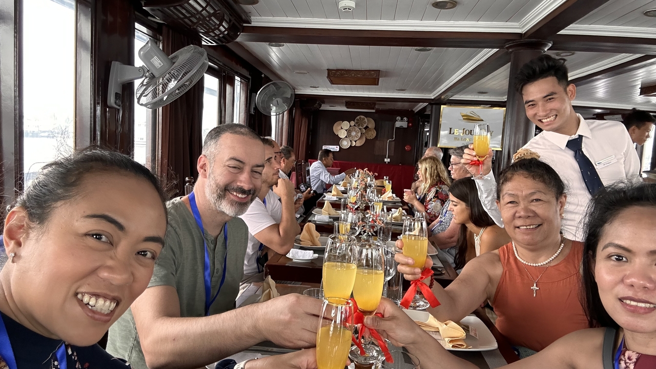 Groupe de personnes trinquant avec leurs boissons sur un bateau.