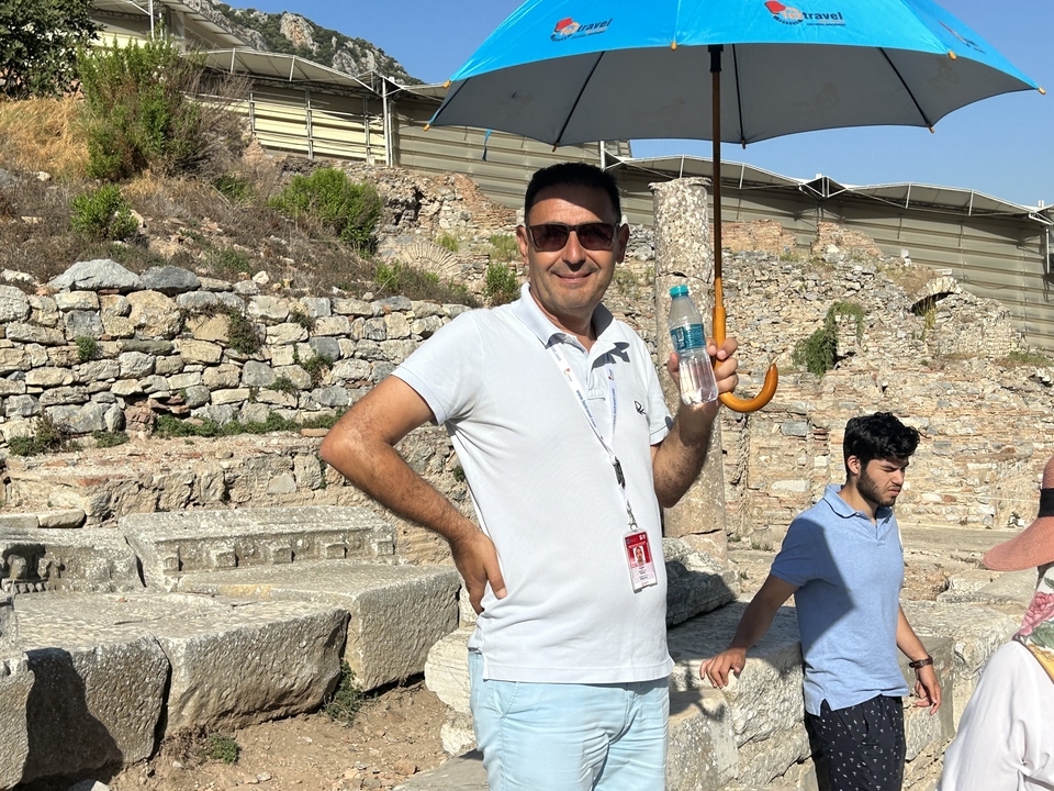 Homme tenant un parapluie et une bouteille d'eau au milieu de ruines