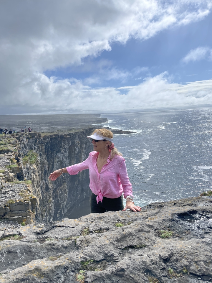 Femme debout près des falaises avec vue sur l'océan.