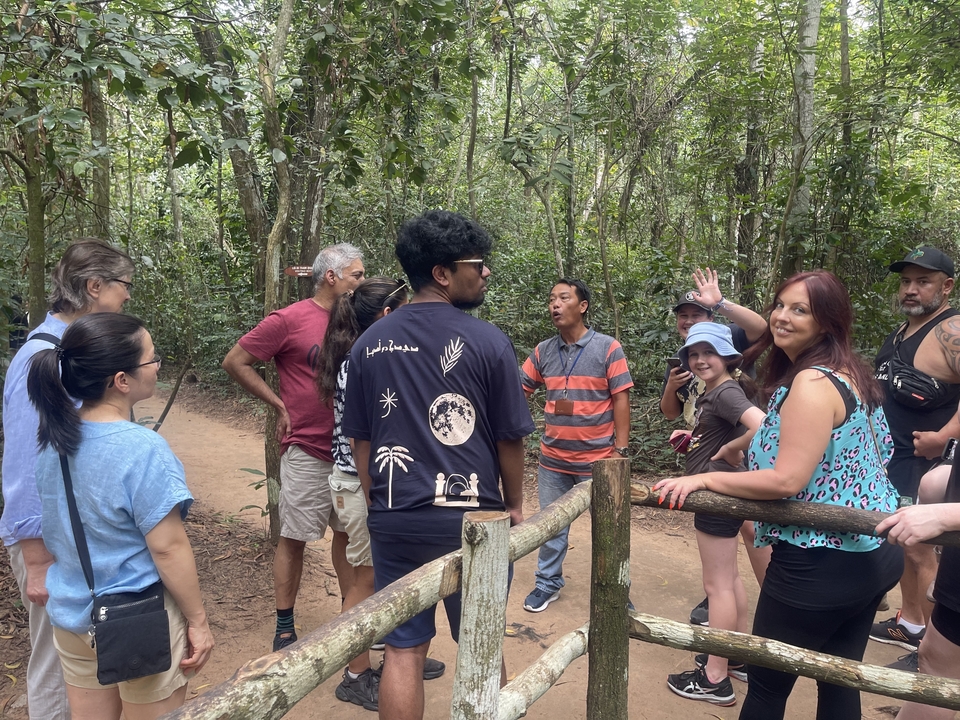 Groupe de touristes dans une zone boisée écoutant un guide.