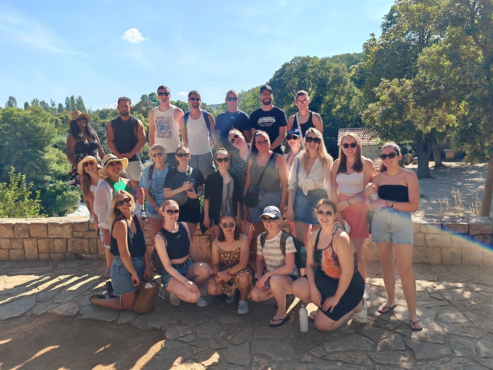 Grand groupe de personnes posant en extérieur sous un soleil éclatant.