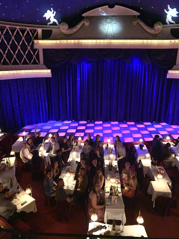Groupe de personnes assises dans un théâtre avec un sol à damier.