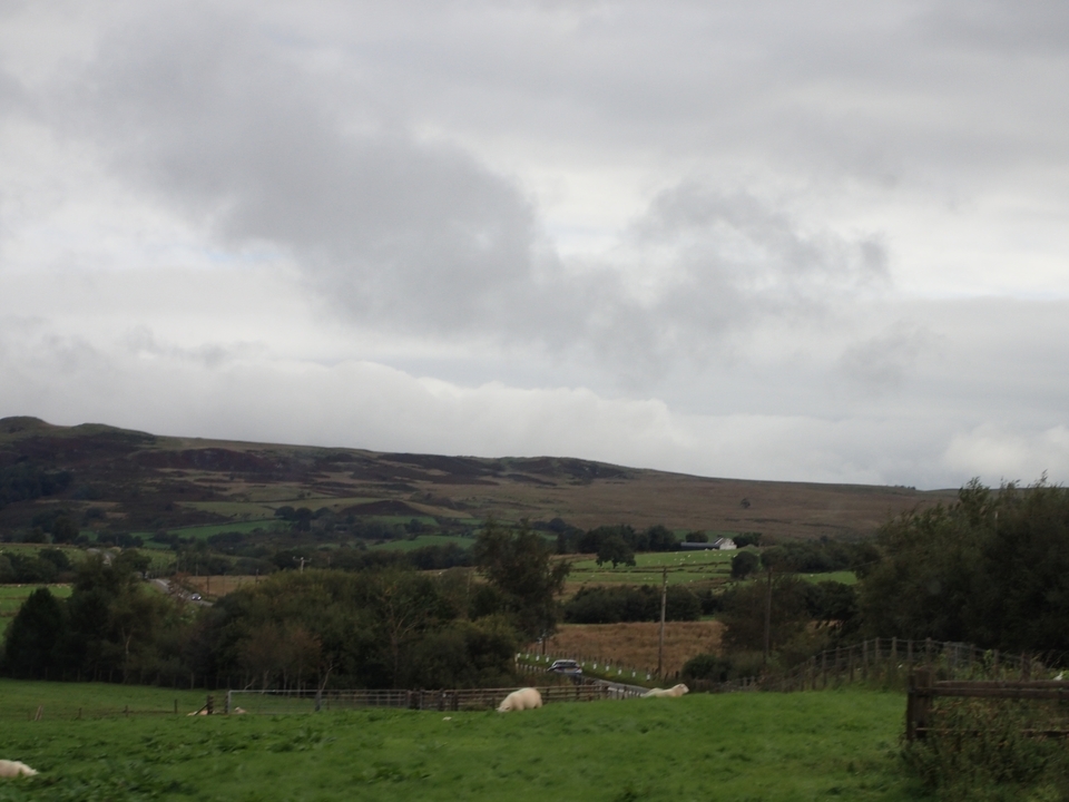 Vue de paysage nuageux sur des collines et des champs.