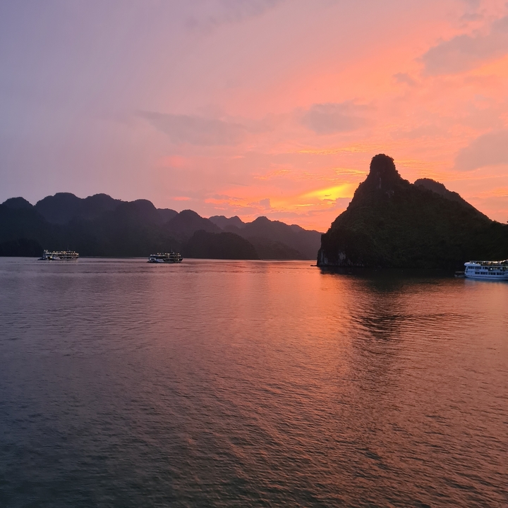 Bateaux naviguant dans la baie d'Halong au coucher du soleil