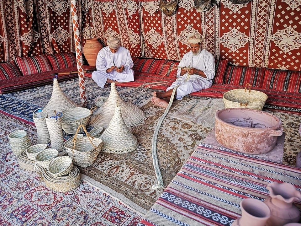 Men engaged in traditional weaving inside a tent.