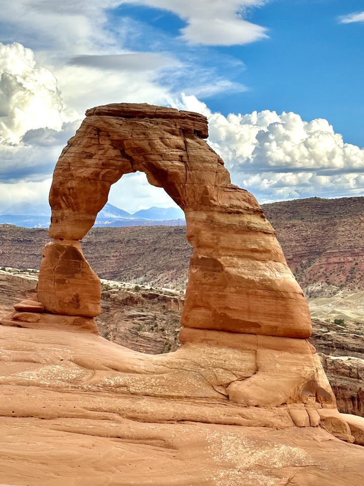 Arche Délicate entourée d'un paysage désertique rocheux sous un ciel nuageux.