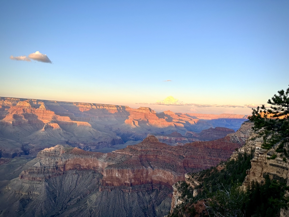 Vue immense du Grand Canyon au coucher du soleil avec des formations rocheuses stratifiées.