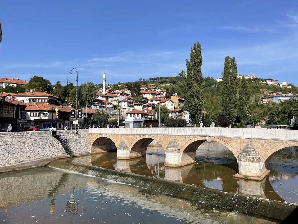 Pont de pierre historique enjambant une rivière avec une ville en arrière-plan.