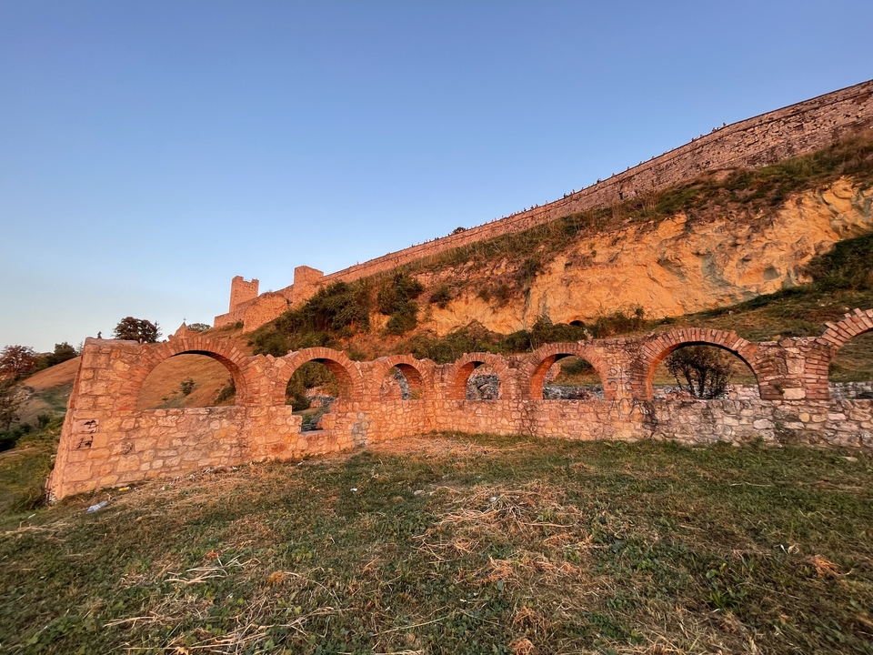 Ruines antiques avec arches au coucher du soleil.