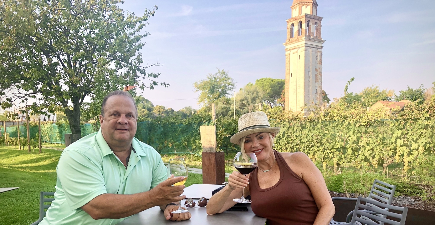 Deux personnes savourant un verre dans un café en plein air avec une tour en arrière-plan.