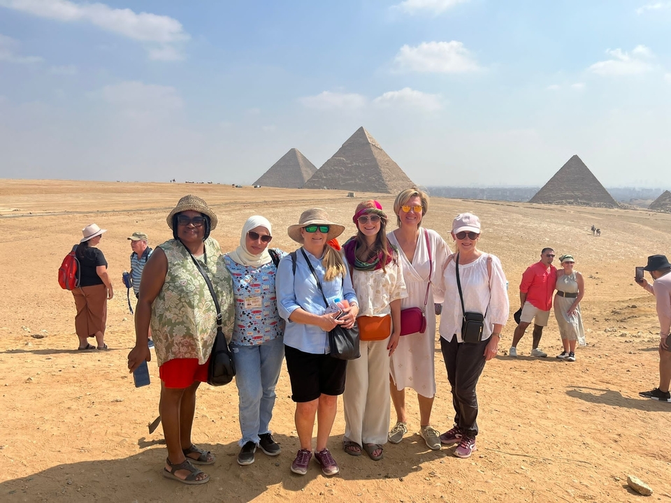 Groupe de personnes posant avec des pyramides en arrière-plan.