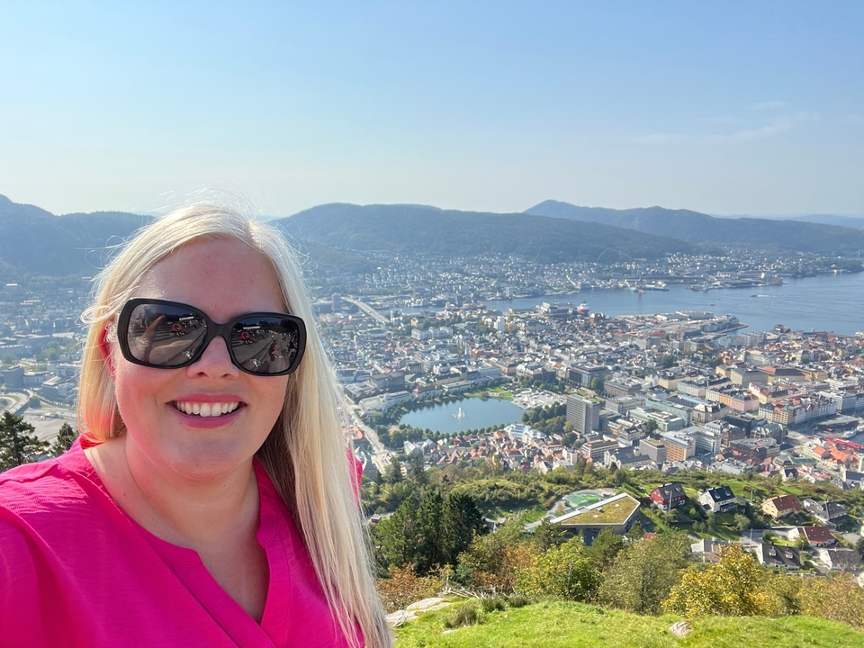 Vue panoramique d'une ville avec une personne au premier plan, journée ensoleillée.
