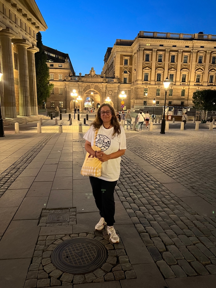 Femme debout sur une rue pavée la nuit.