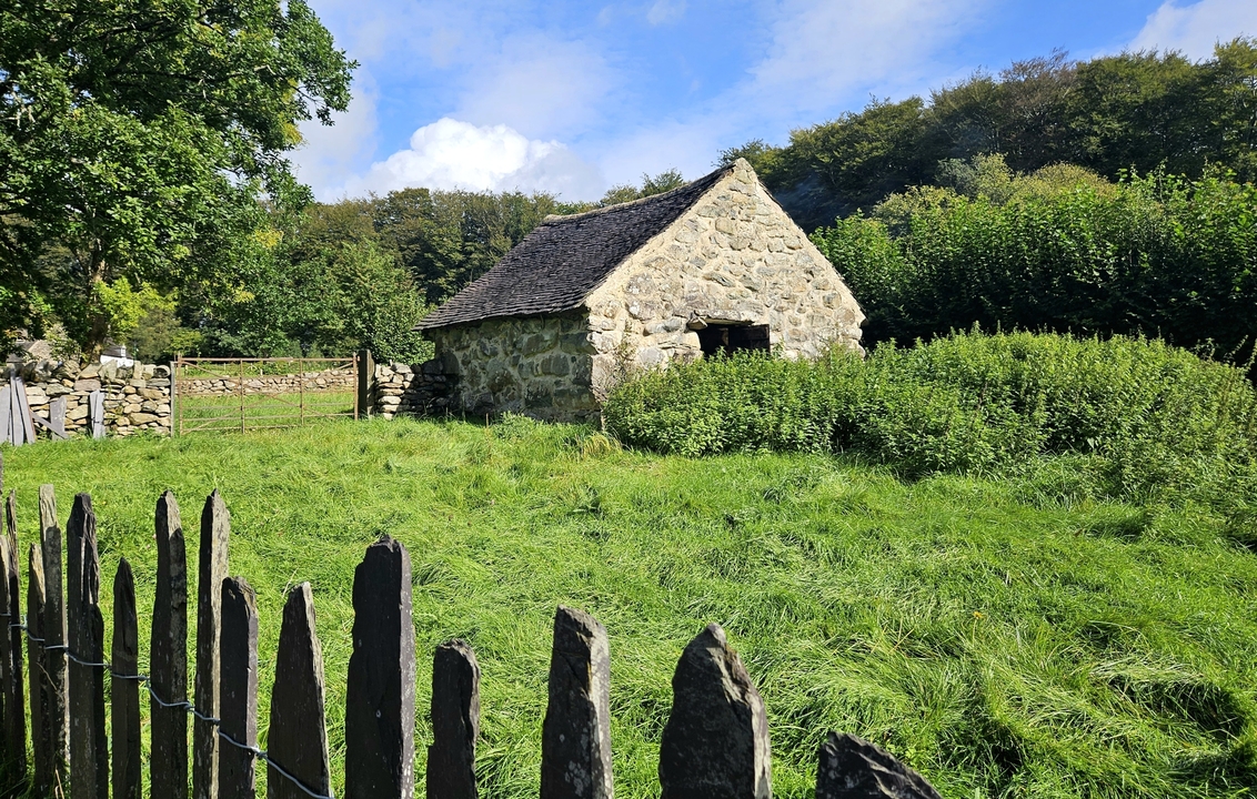 Petit bâtiment en pierre entouré d'une végétation luxuriante.
