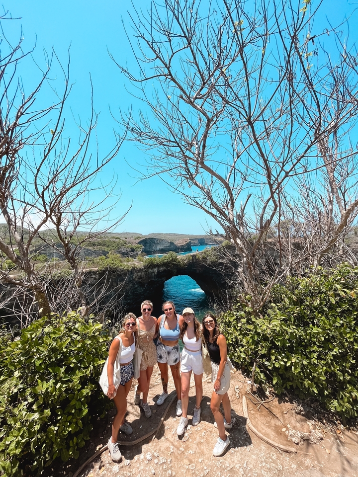 Groupe de personnes à une formation rocheuse naturelle avec vue sur l'océan.
