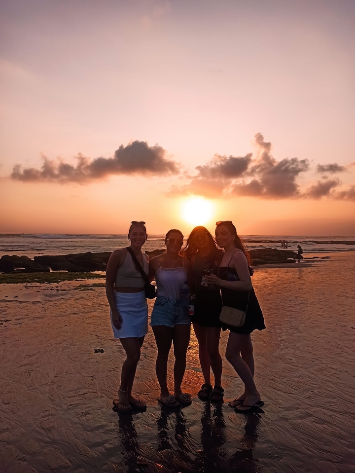 Groupe d'amis profitant d'un coucher de soleil à la plage.