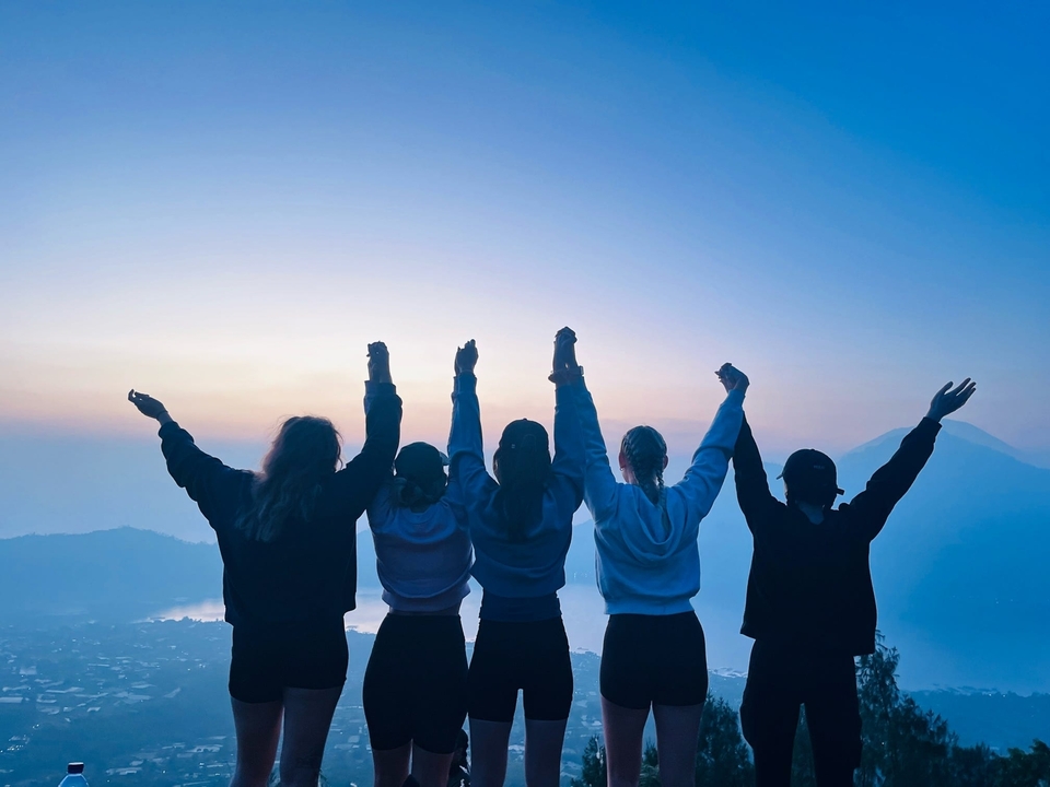 Silhouettes de personnes levant les mains au lever du soleil.