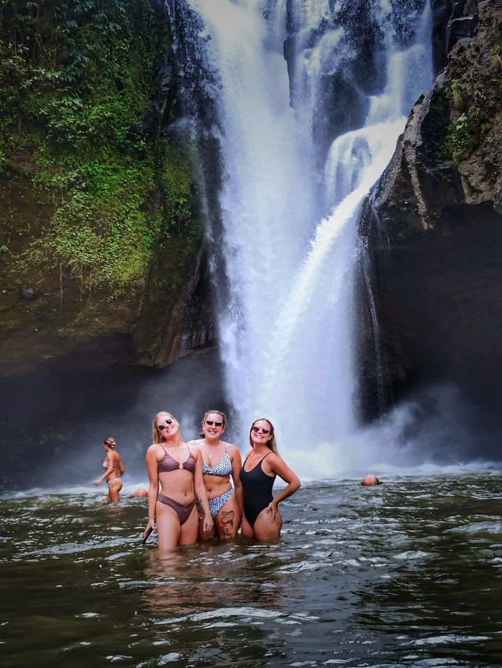 Trois femmes posant devant une grande cascade.