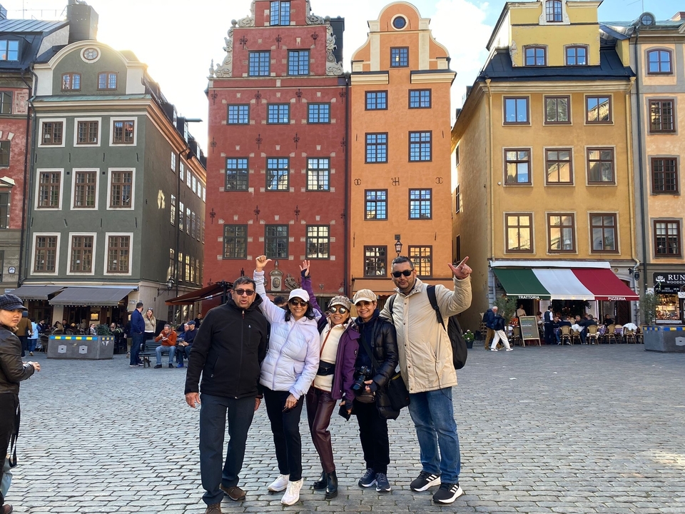 Groupe de personnes devant des bâtiments colorés sur une place de la ville.