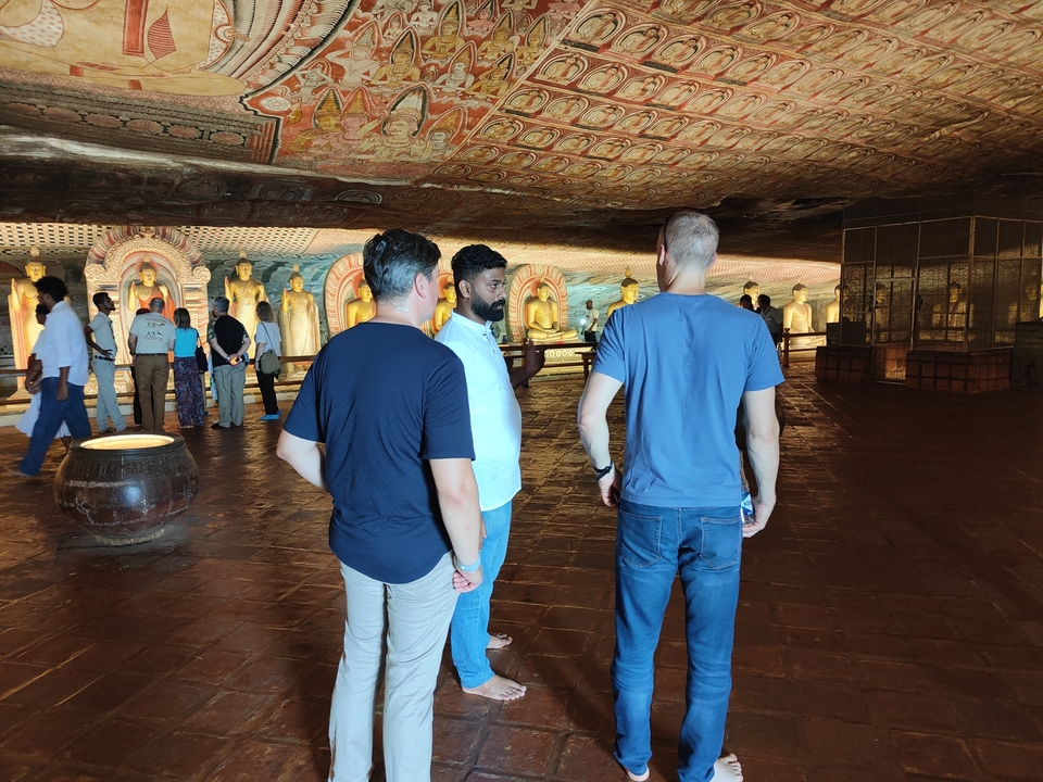 Des personnes à l'intérieur d'un temple avec des statues de Bouddha en arrière-plan.