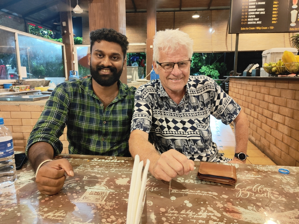 Deux personnes assises à une table, souriant à la caméra.