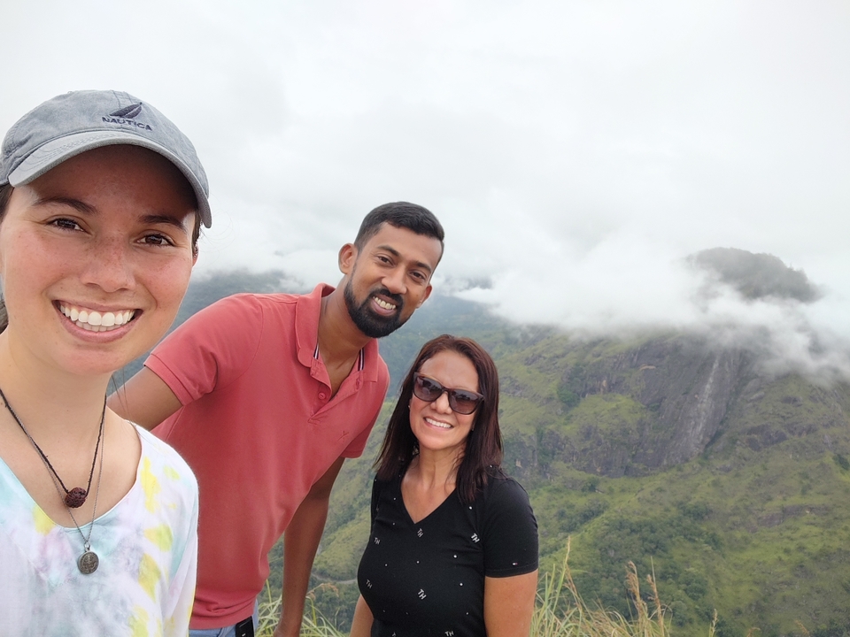 Trois personnes posant dans un paysage vallonné pittoresque avec de la brume.