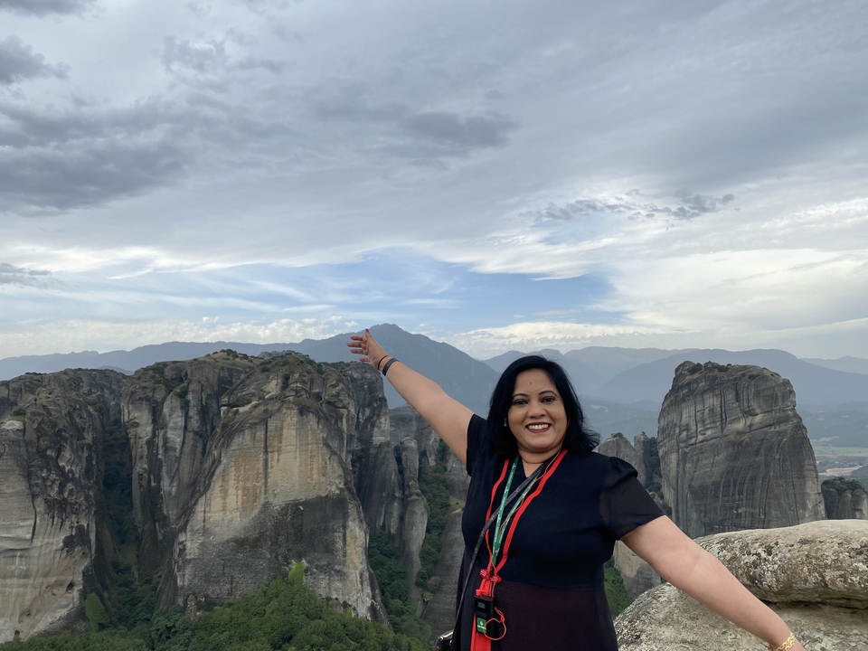 Une personne qui pose les bras étendus devant des formations rocheuses.