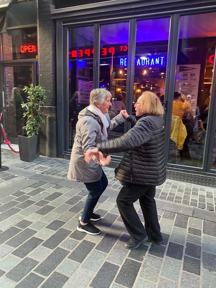 Deux personnes dansant joyeusement dans une rue.