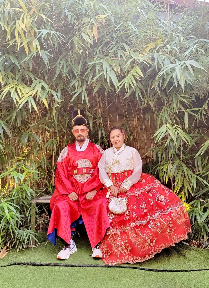 Un couple vêtu d'habits traditionnels assis dans un jardin.