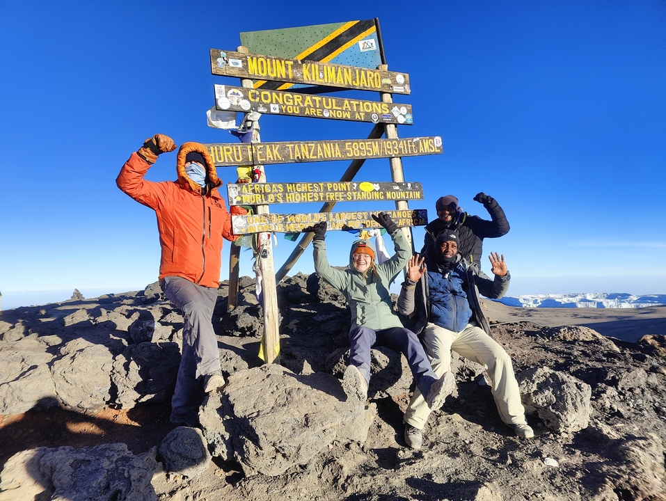 Randonneurs heureux au sommet Uhuru avec un panneau.