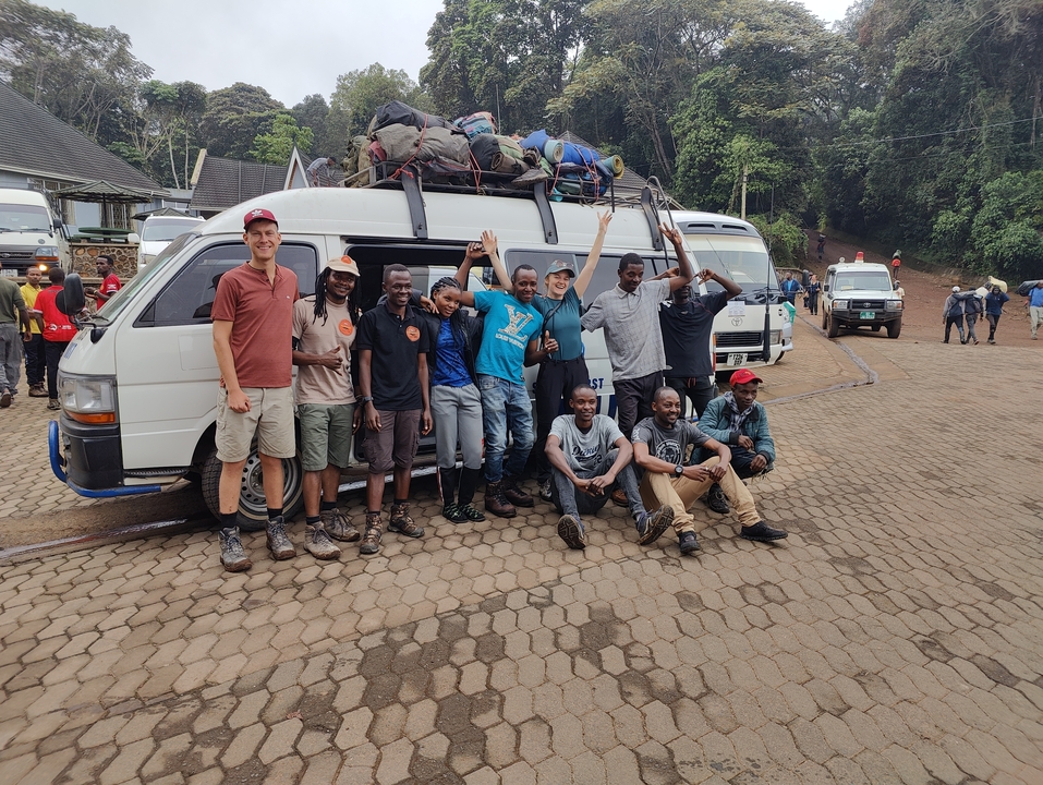 Un grand groupe de personnes posant devant un van de tournée.