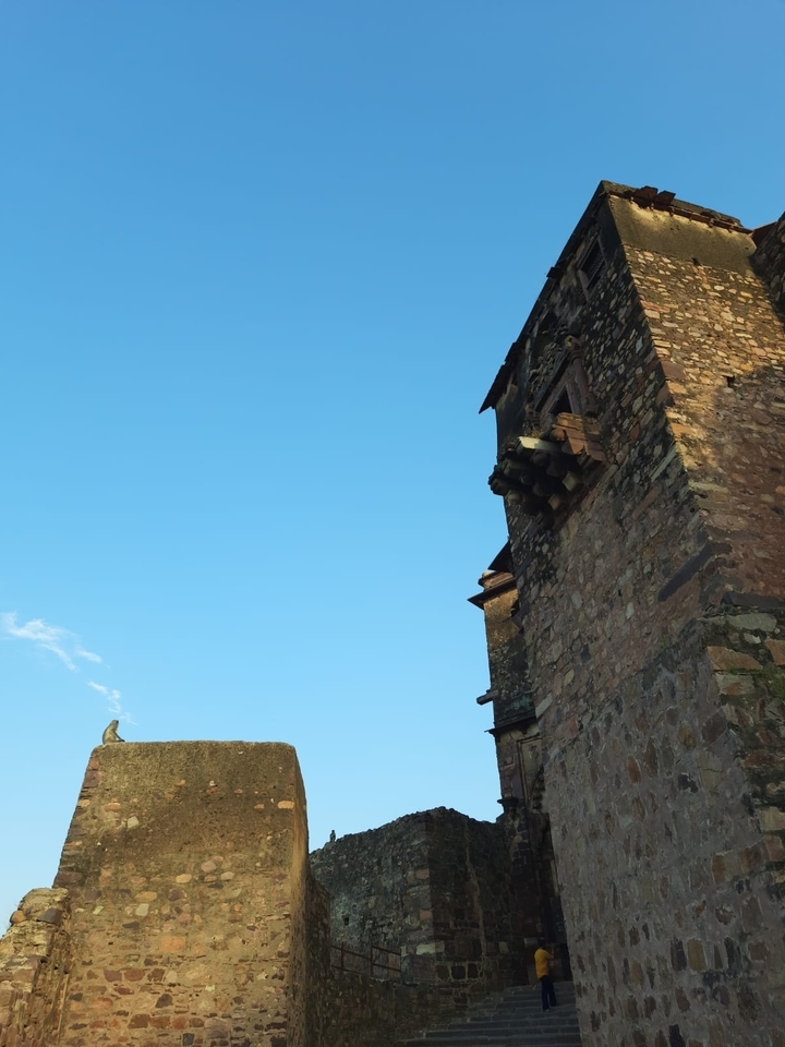 Partie d'un bâtiment en pierre contre un ciel dégagé.
