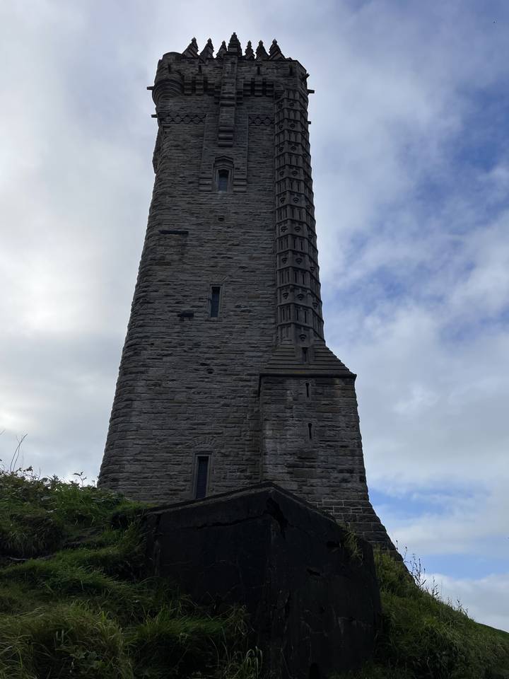 Une haute tour de pierre aux sculptures complexes sur fond de ciel nuageux.