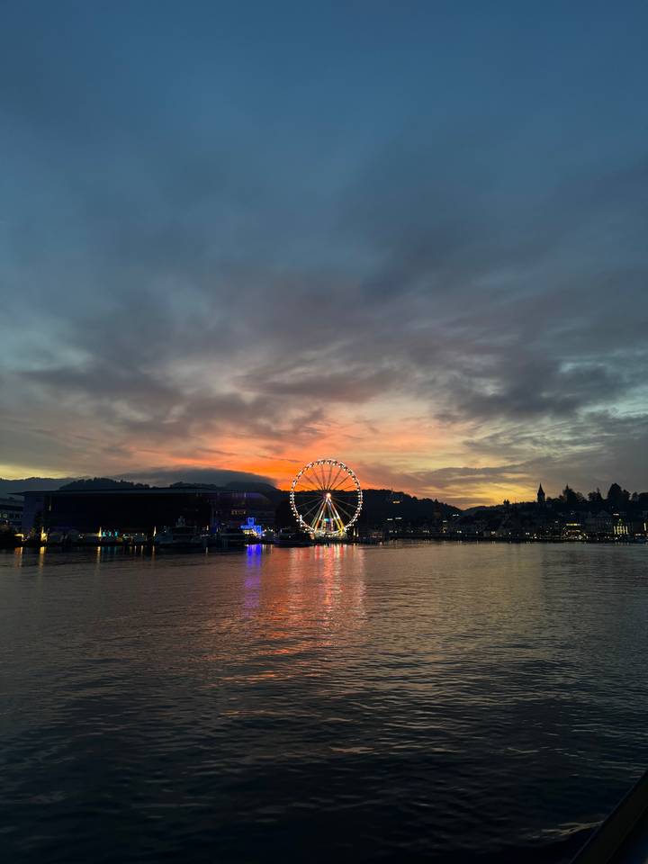 Grande roue au coucher du soleil au-dessus d'un plan d'eau.