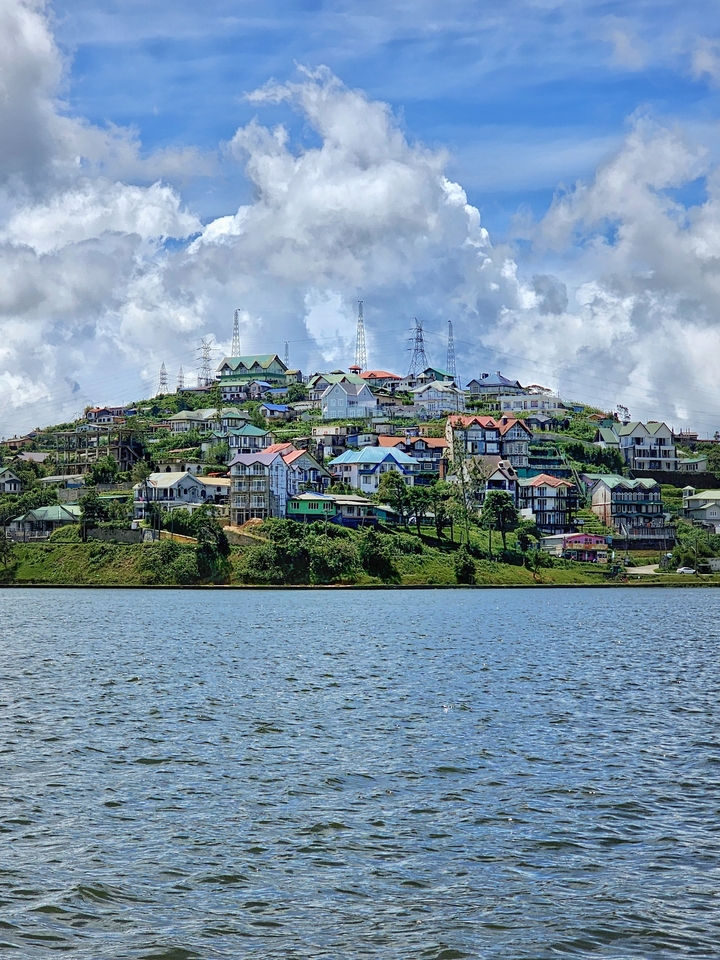 Maisons colorées sur une colline près d'un plan d'eau.