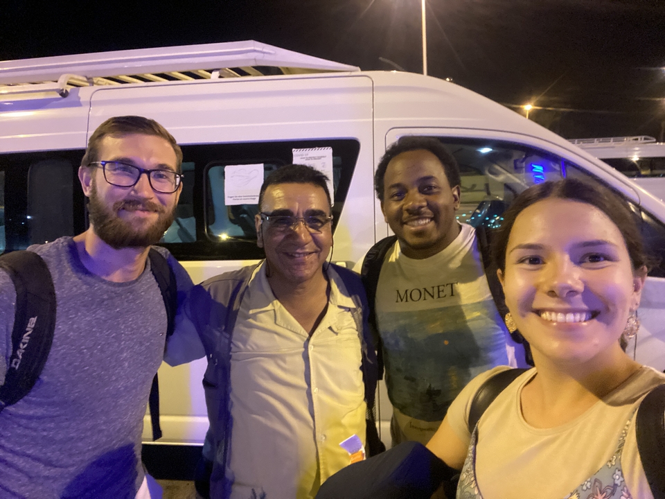Groupe de personnes posant devant un véhicule la nuit.