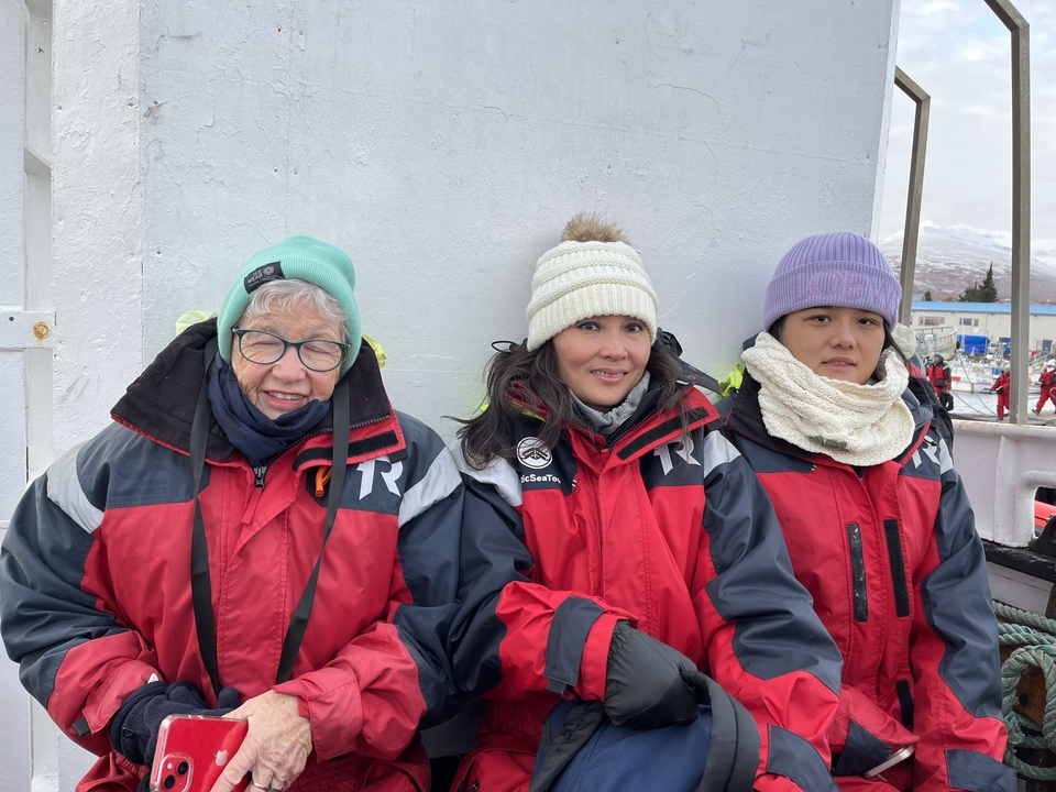 Trois personnes en vêtements chauds sur un bateau.