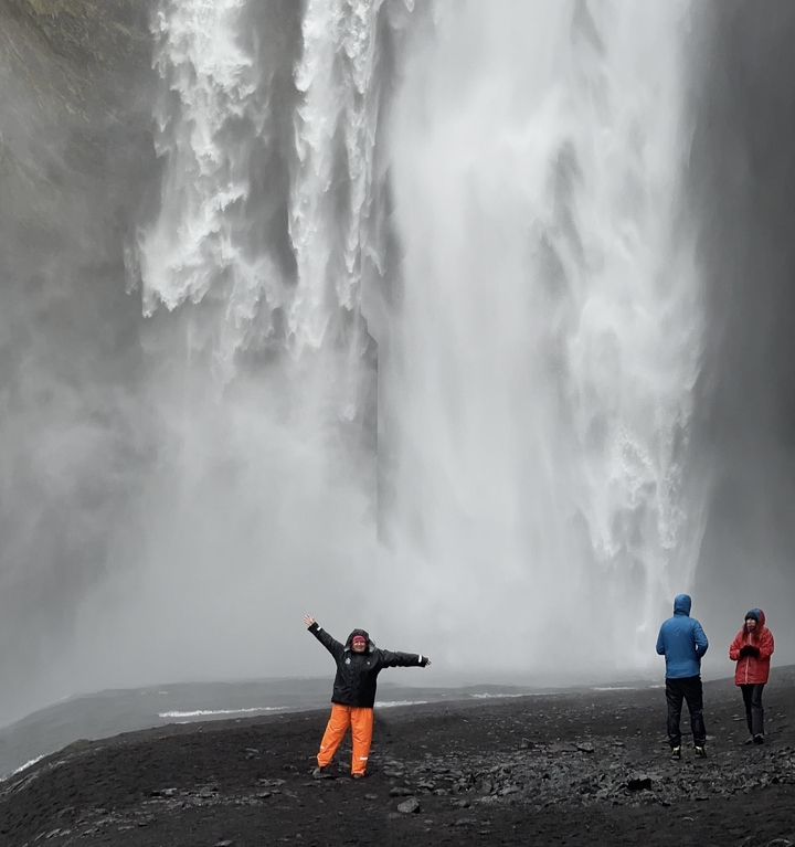 Deux personnes observant une chute d'eau imposante de près.