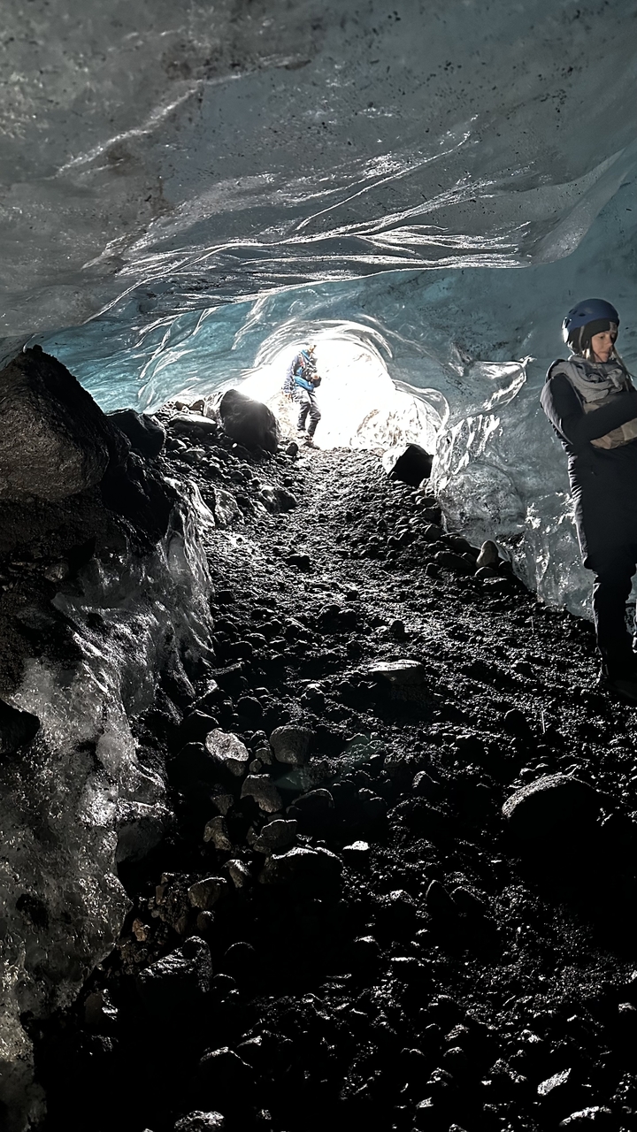 Des personnes explorant un passage de grotte sombre et glacé.