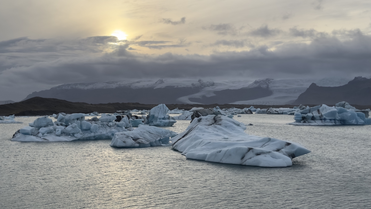 Icebergs flottant dans un lagon sous un ciel nuageux.